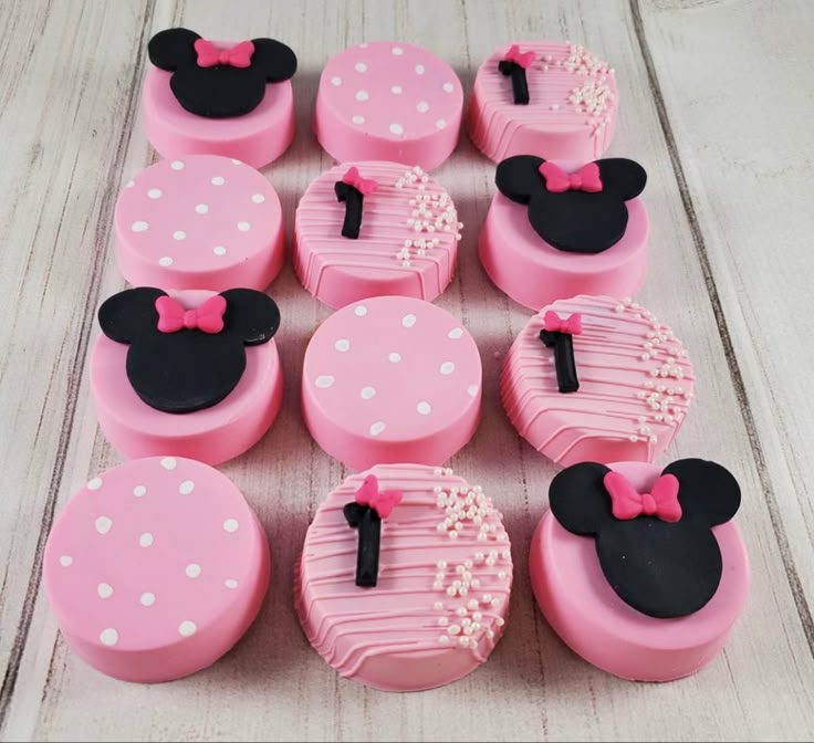 pink and black mickey mouse cupcakes are arranged on a white table with polka dots