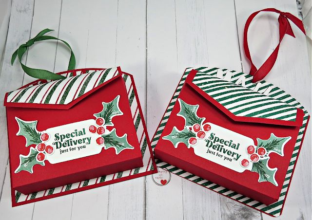 two red and green christmas gift bags sitting on top of a white wooden table next to each other