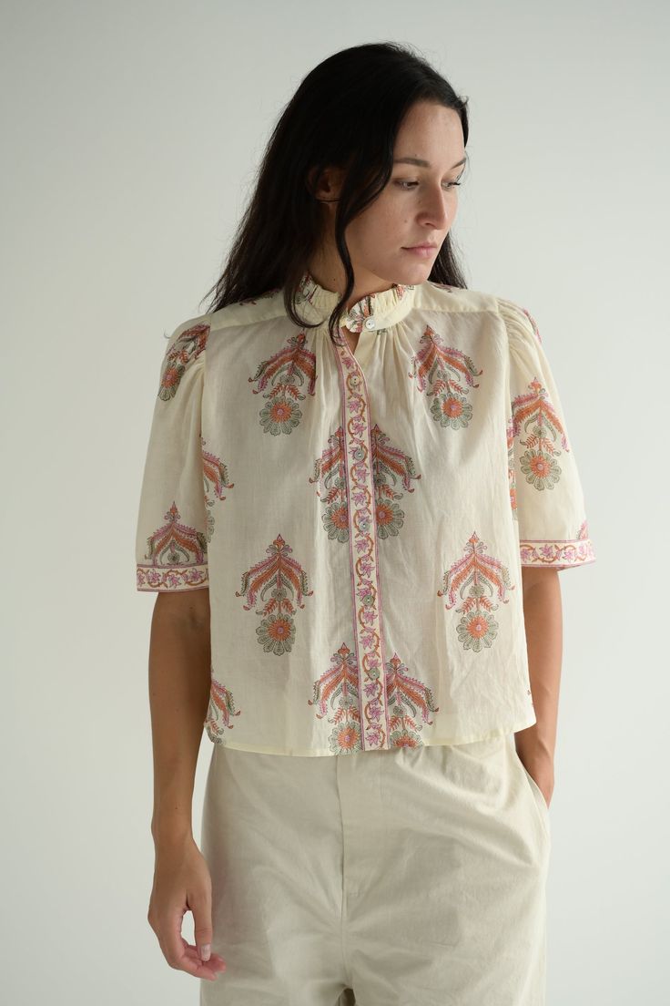 The Alix of Bohemia Winnie Shirt has a puffed sleeve, ruffled collar and Mother of Pearl button front. Color Guava Cactus Flower is a creamy off-white featuring pinks, greens and oranges in the print. This one-of-a-kind textile was block-printed by hand in a gorgeous floral motif. Subtle printing and dye variations are part of the unique beauty of the garment and a signature of the artisan’s hand. 100% Cotton. Made in India. Adeline is 5'7" wearing size Extra Small. Block Printed Clothes, Green Floral Blouse, Peter Pan Collar Blouse, Floral Button Up, Petal Sleeve, Indian Prints, Ruffled Collar, Cactus Flower, Mother Of Pearl Buttons