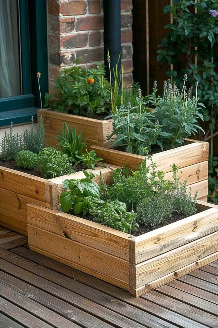 three wooden planters filled with plants on top of a wooden floor next to a brick building