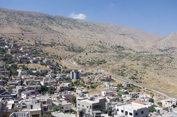 an aerial view of a city with hills in the background and buildings on either side