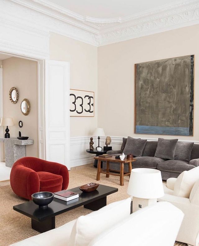 a living room filled with furniture and a painting hanging on the wall above it's fireplace