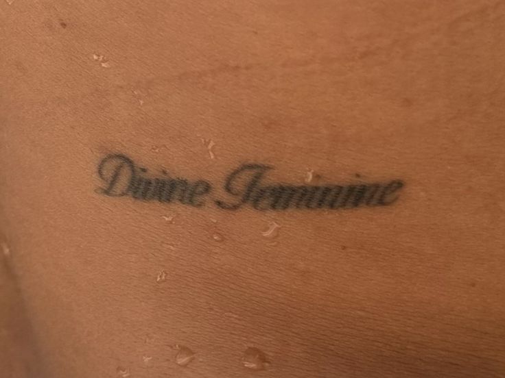 a woman's back with the word dance feminine written in black ink on it