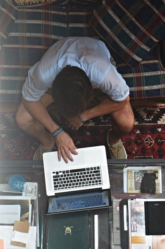 a man sitting on top of a couch next to a laptop computer and other items