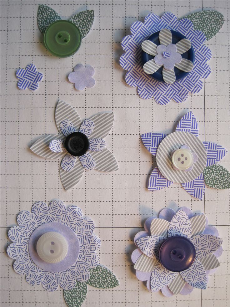 several different types of buttons and flowers on a piece of paper that has been cut out