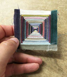 someone is holding a piece of art made out of felt and fabric with different colors