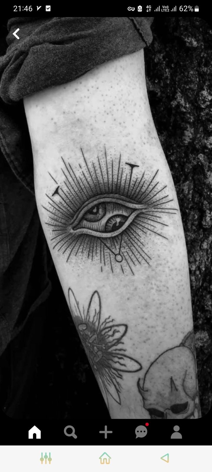 a black and white photo of an eye with sunflowers on the forearm, next to a skull