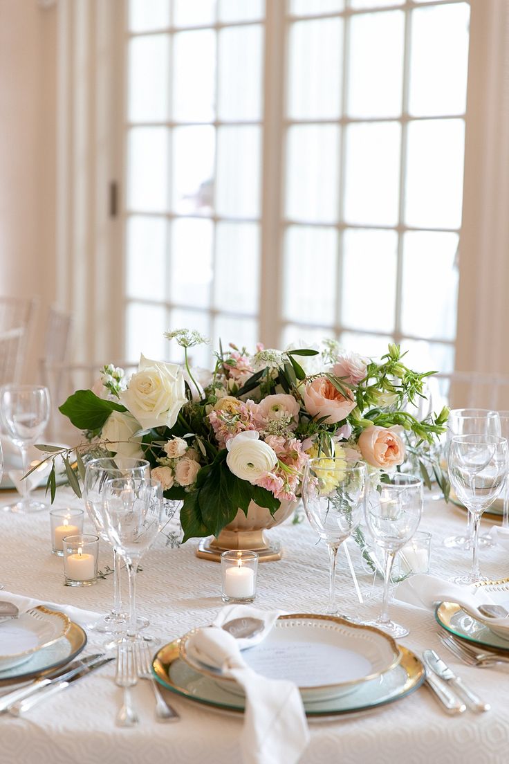 the table is set with white and pink flowers, silverware, and wine glasses