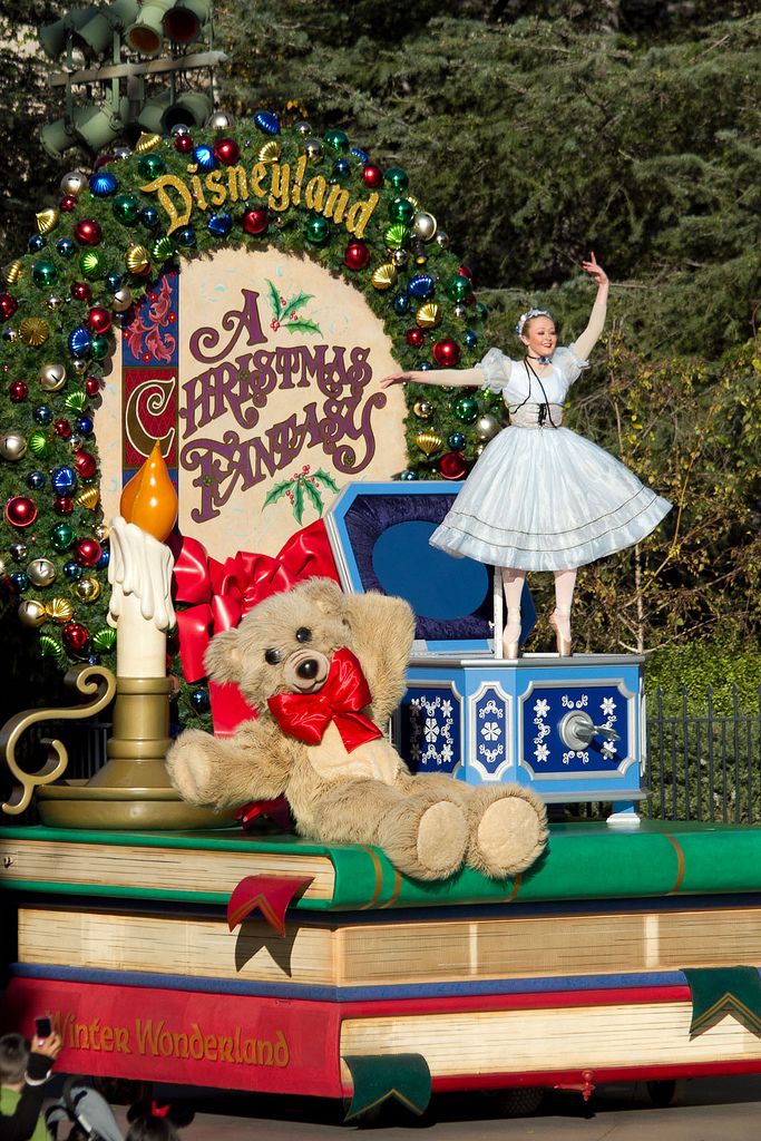 a teddy bear sitting on top of a pile of books in front of a christmas display