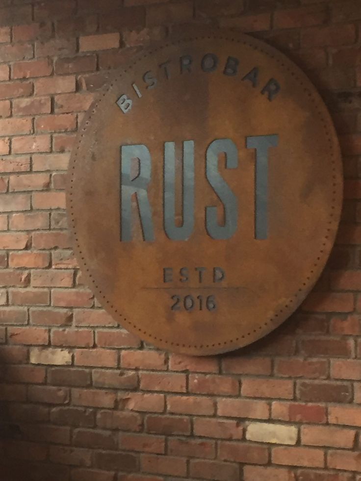 the rust sign is hanging on the brick wall in front of a clock that reads bistrobar rust