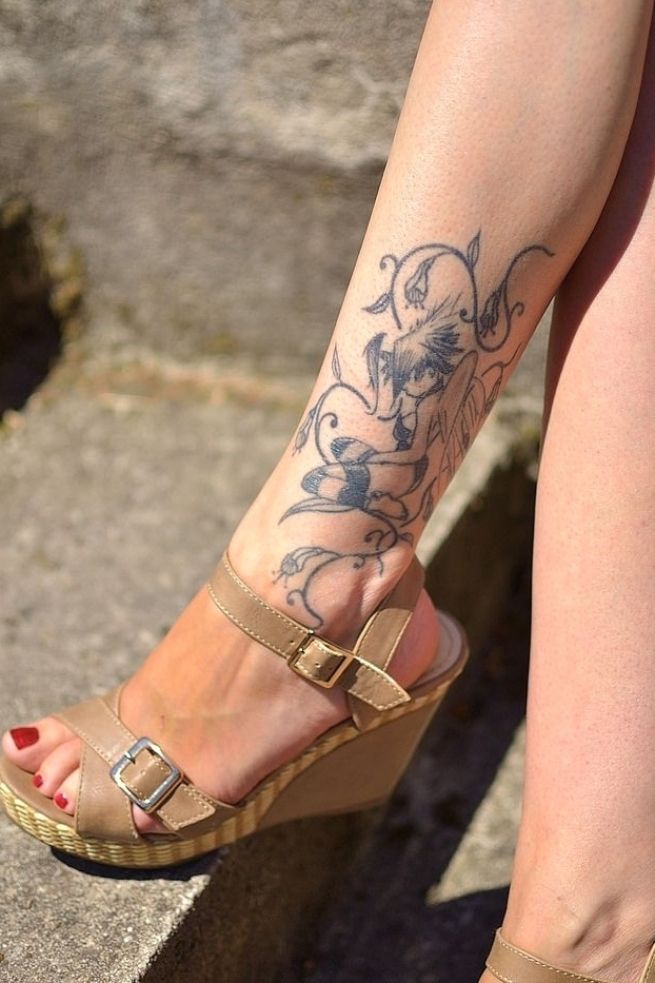 a woman's legs with tattoos on them sitting on some steps and wearing sandals