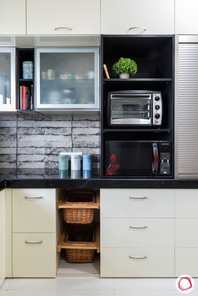 a kitchen with white cabinets and black counter tops, including an open microwave above the sink