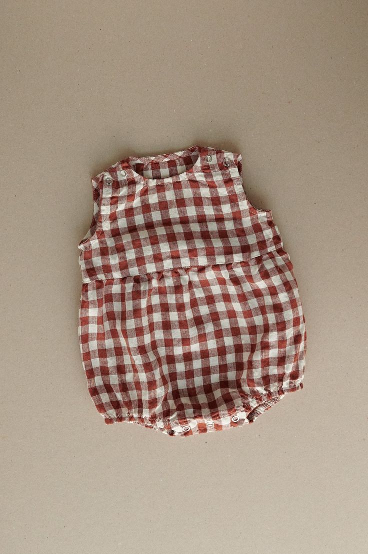 Product photos - terracotta gingham. The model is wearing a romper in yellow gingham. All-day comfort is guaranteed with this sleeveless romper crafted gingham linen. The fabric is soft, breathable, and light on the skin. For simple changing, the romper is designed with popper snap fastenings on the shoulders and bottom. The waist seam in the middle adds a nice final touch to an adorable silhouette, and elasticated leg cuffs secure the romper in place. This baby romper is designed to be comfortably loose-fitting and allow for growth as the baby grows. Plaid Cotton Bubble Romper For Summer, Summer Cotton Plaid Bubble Romper, Summer Plaid Cotton Bubble Romper, Summer Brown Cotton Jumpsuits And Rompers, Brown Cotton Jumpsuits And Rompers For Summer, Summer Gingham Cotton Bubble Romper, Cute Gingham Cotton Bubble Romper, Cute Cotton Gingham Bubble Romper, Spring Gingham Jumpsuits And Rompers