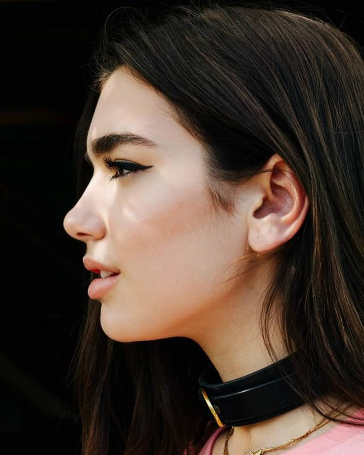 a close up of a woman wearing a choker and looking off into the distance