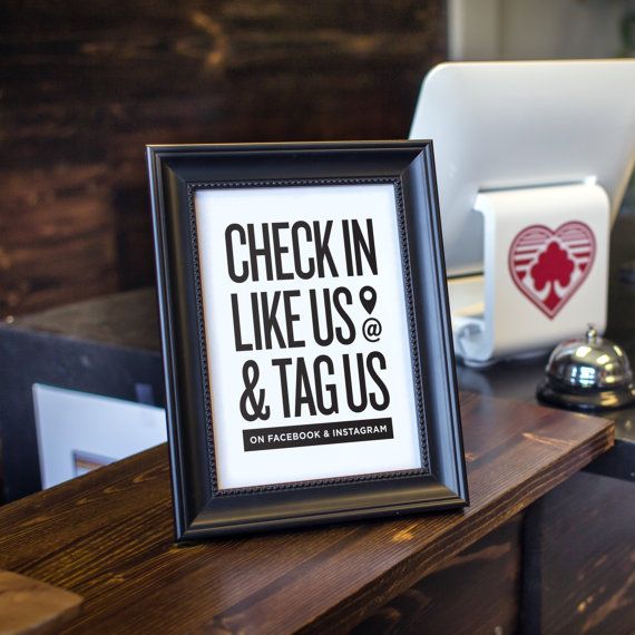 a framed sign sitting on top of a wooden table next to a laptop and mouse