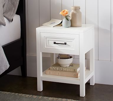 a white nightstand table with books and flowers on it