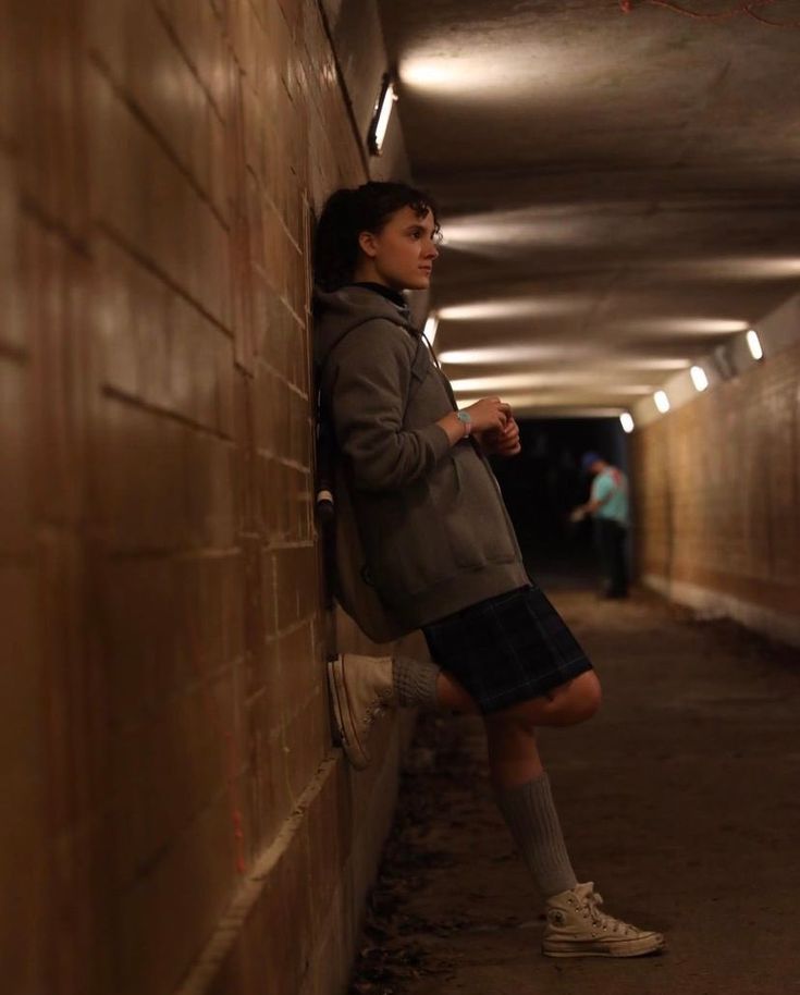 a person leaning against a wall in a tunnel