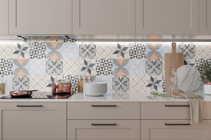 a kitchen with grey cabinets and white countertops has colorful tiles on the backsplash