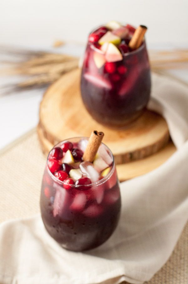 two glasses filled with pomegranate and cinnamon sticks