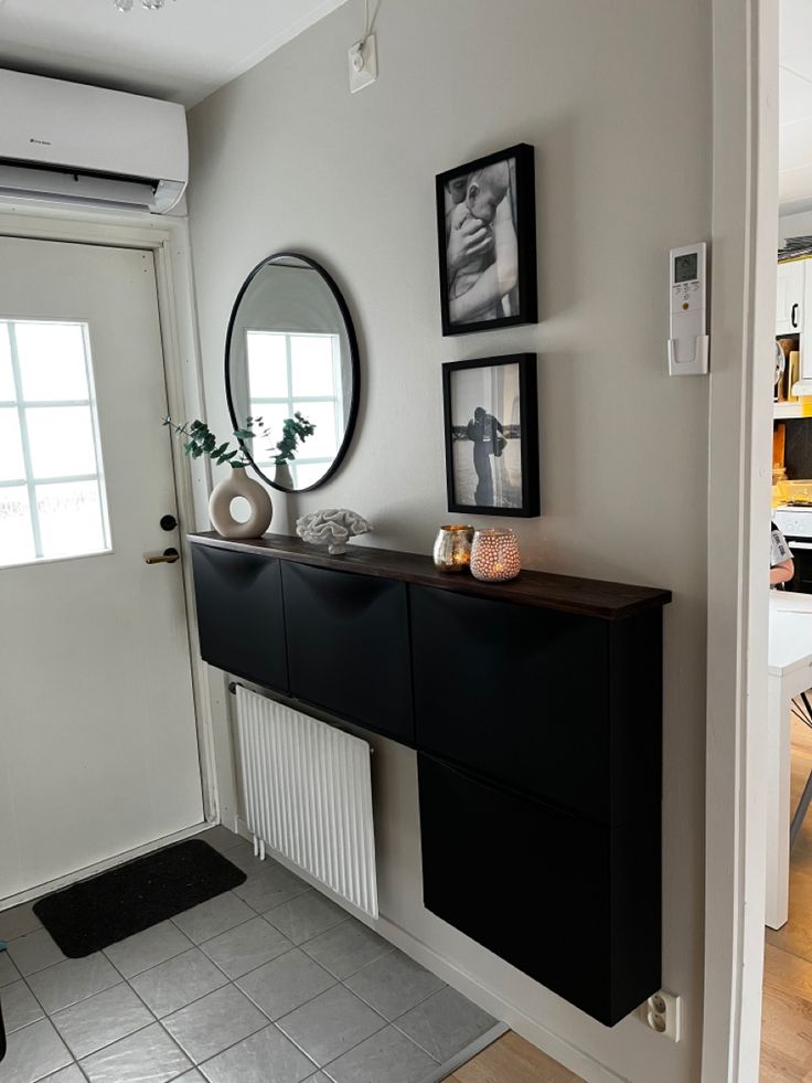 a black and white room with pictures on the wall, a mirror and a radiator