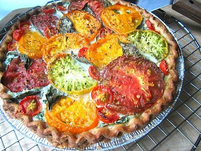 a pie with tomatoes and other toppings sitting on top of a metal cooling rack