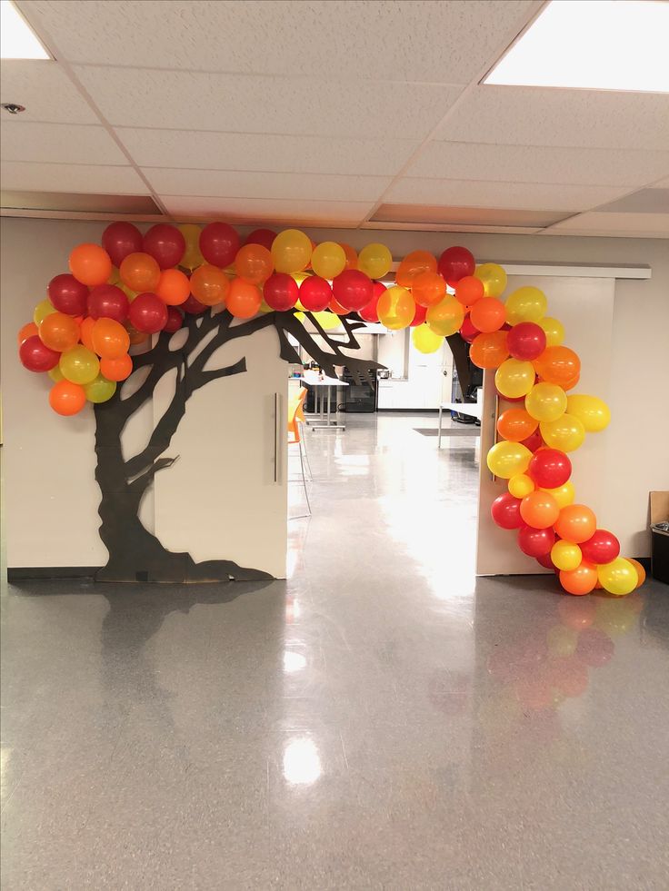 an arch made out of balloons is in the middle of a hallway that has a tree on it