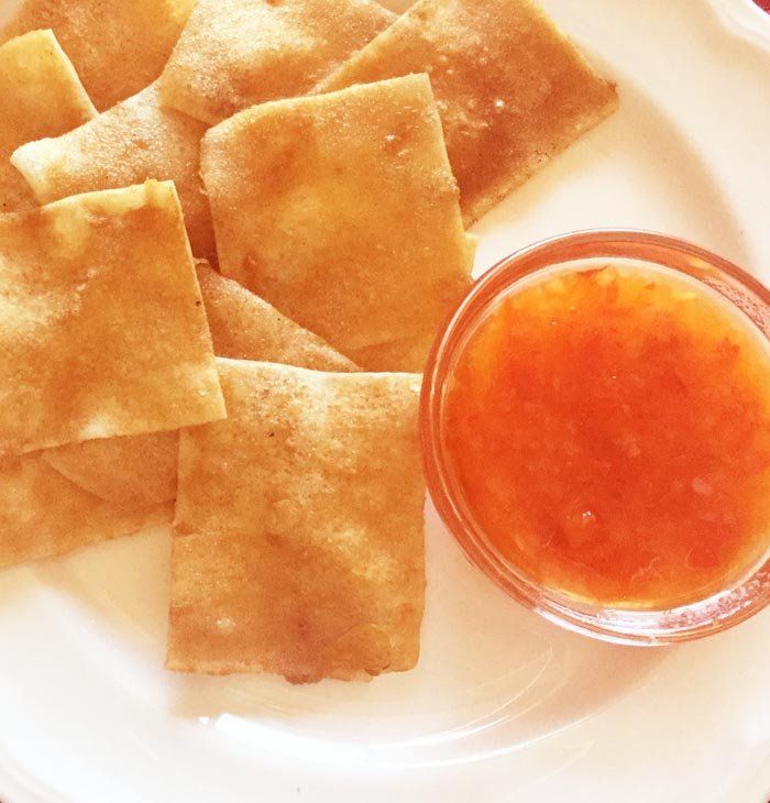 some food on a white plate with a small bowl of sauce next to the pita chips