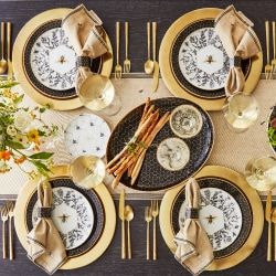 an overhead view of a table setting with gold and black plates, napkins and flowers