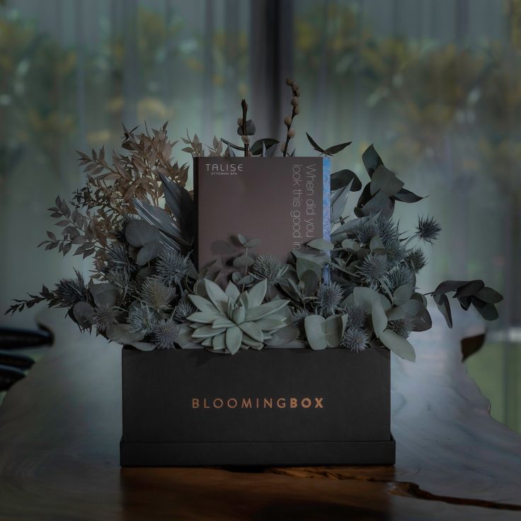 an arrangement of flowers in a black box on a table