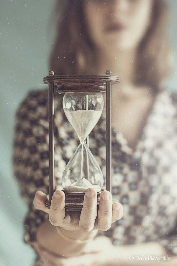 a woman holding an hourglass in front of her face