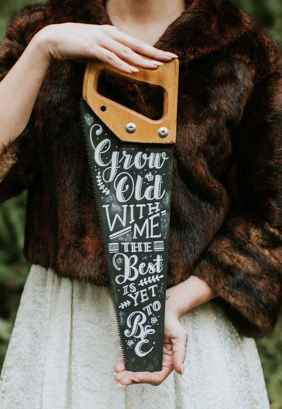 a woman holding up a wooden sign with writing on it's side and a leather handle in her hand