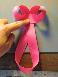 a person pointing at a pink ribbon on a ruler