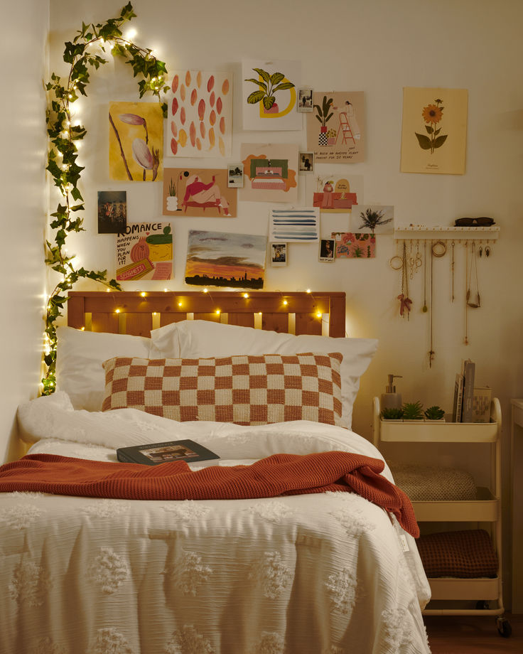 a bed with lots of pictures on the wall above it and lights hanging from the headboard