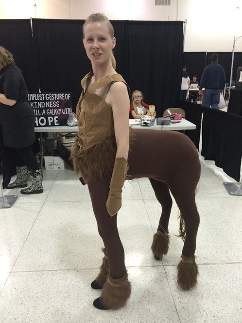 a woman in costume standing next to a horse on display at a convention or show