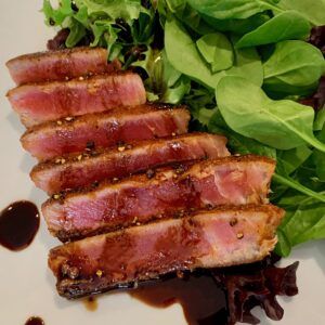 slices of bacon sit on top of lettuce next to a plate of salad