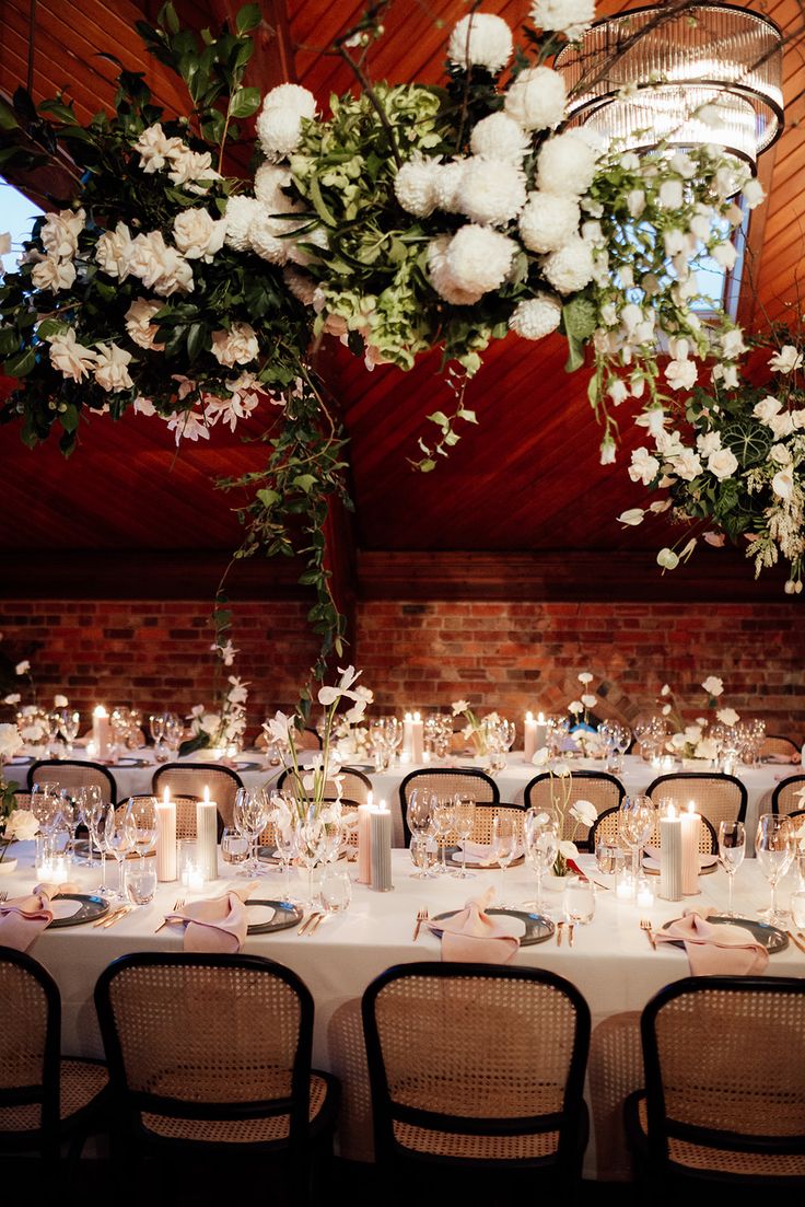 the tables are set with white flowers and candles for an elegant wedding reception at this venue