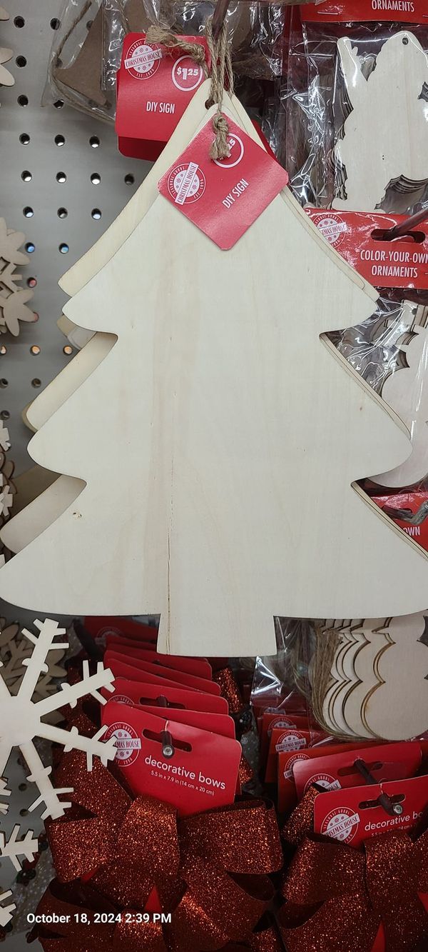 a wooden christmas tree ornament hanging on a shelf in a store with red and white tags