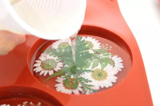 a person pouring water into a bowl with flowers in it