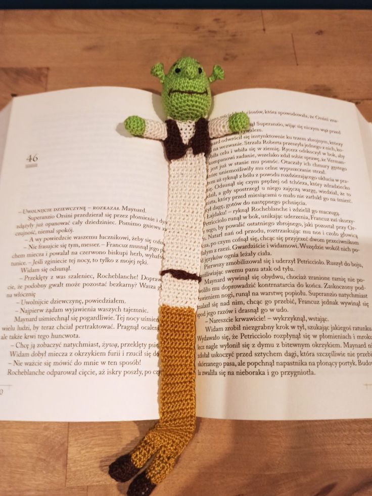 an open book with a crocheted frog on it