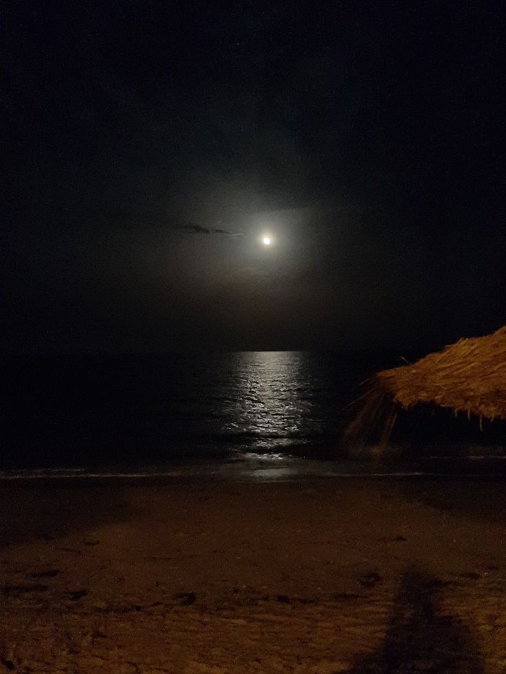 the moon is shining over the ocean at night