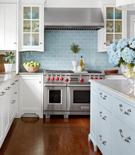 a kitchen with white cabinets and blue backsplash tiles on the walls, along with hardwood floors