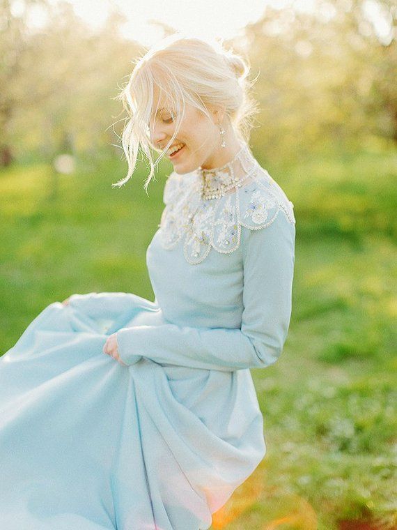 a woman in a blue dress is walking through the grass with her hands on her hips