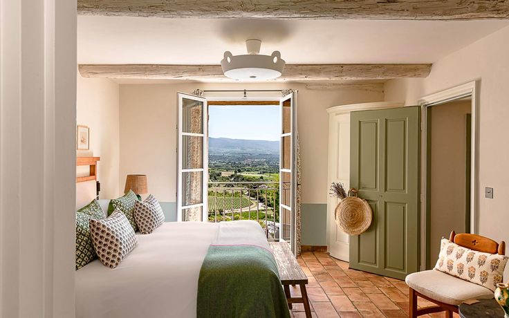 a bedroom with a large bed and a view out the window to the countryside outside