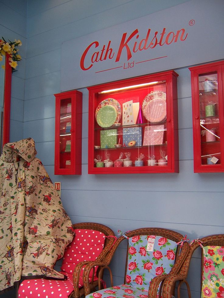 the interior of a store with chairs and cushions in front of red display cases on blue walls