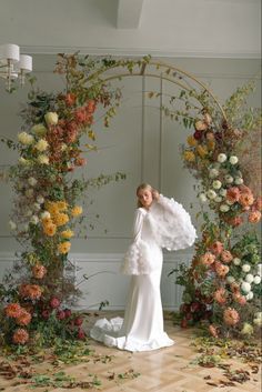 a woman standing in front of a floral arch