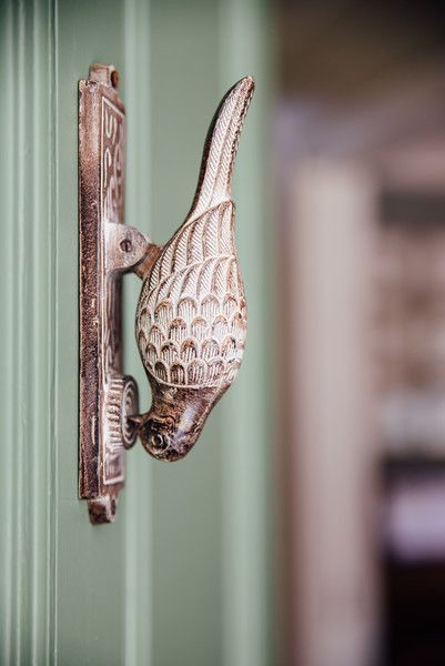 a bird shaped doorknob on the side of a green wall