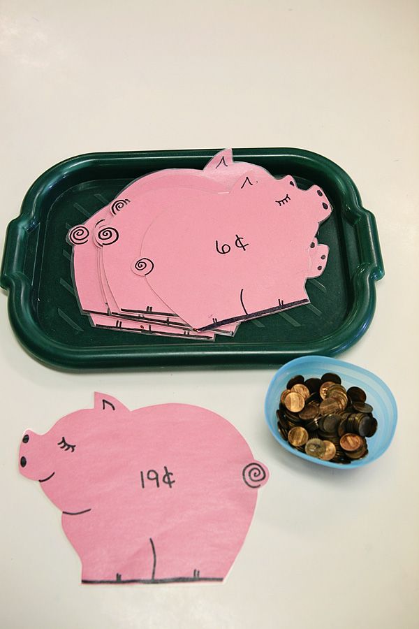 two pig shaped cut outs sitting on top of a table next to a bowl of coins