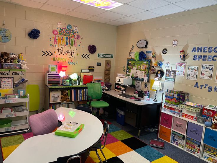 a room filled with lots of books and desks next to a wall covered in pictures