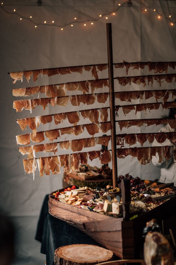 a boat made out of bacon is on display in a room with string lights hanging from the ceiling