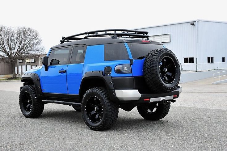 a blue and black jeep parked in front of a building